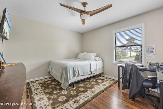 bedroom with dark hardwood / wood-style floors, a textured ceiling, and ceiling fan