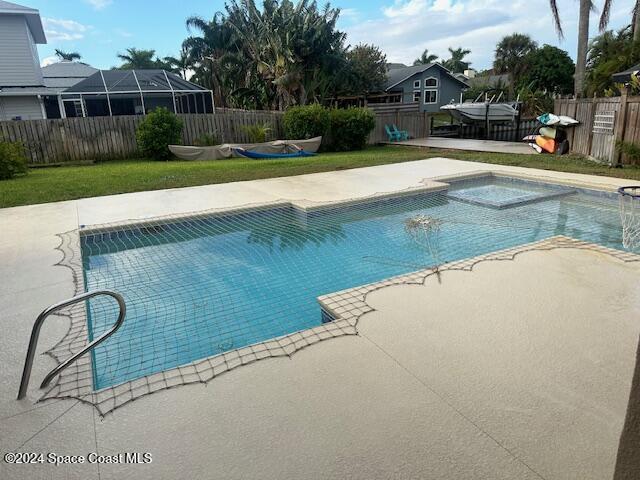 view of pool featuring a jacuzzi, a lawn, and a patio