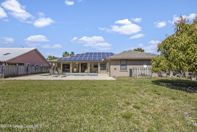 rear view of house with a fenced in pool, a patio, a yard, and solar panels