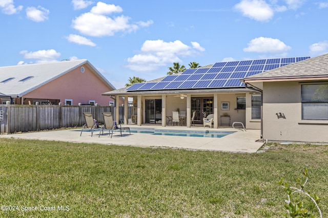 rear view of house featuring a fenced in pool, a lawn, a patio area, and solar panels