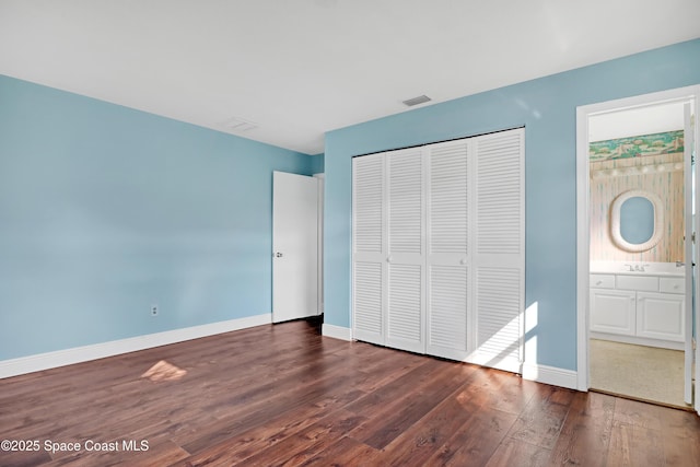 unfurnished bedroom with connected bathroom, a closet, sink, and dark hardwood / wood-style floors