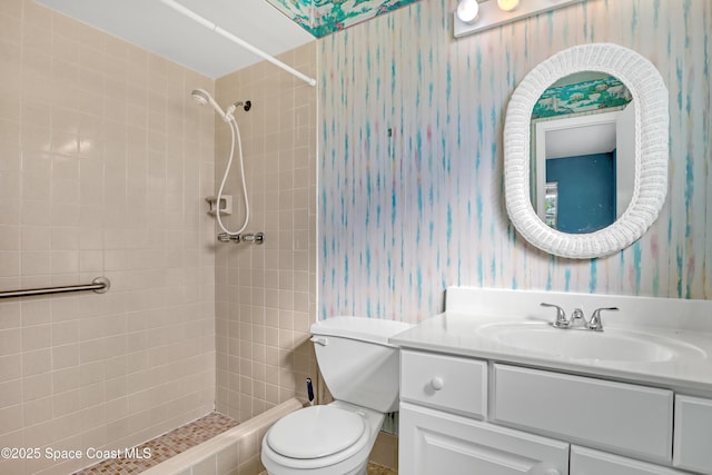 bathroom with tiled shower, vanity, and toilet