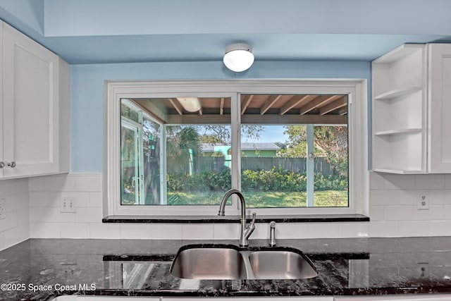 kitchen with white cabinetry, sink, dark stone countertops, and backsplash