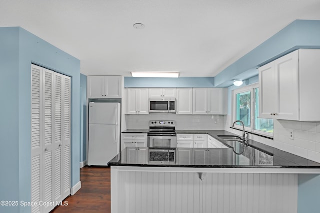 kitchen featuring white cabinetry, appliances with stainless steel finishes, kitchen peninsula, and sink