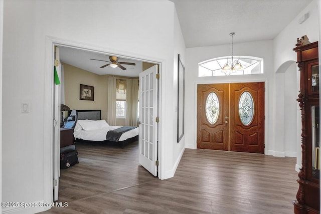 foyer featuring dark wood-type flooring, high vaulted ceiling, a healthy amount of sunlight, and an inviting chandelier