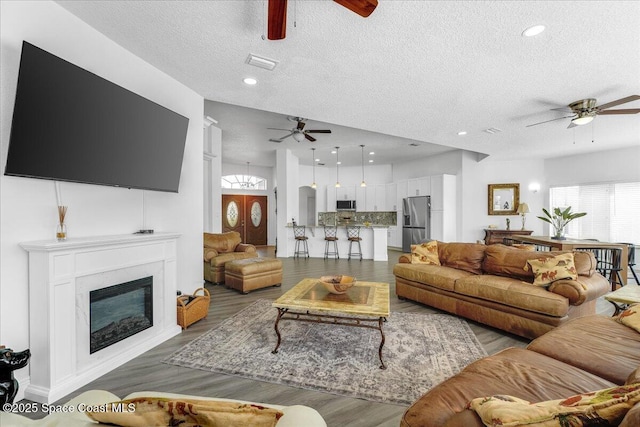 living room featuring hardwood / wood-style floors, a textured ceiling, and ceiling fan