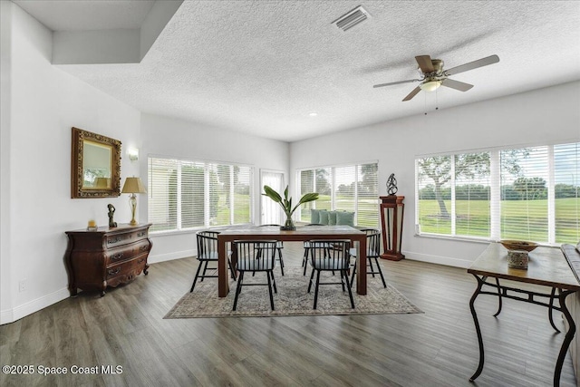 dining area featuring ceiling fan, dark wood-type flooring, and a textured ceiling