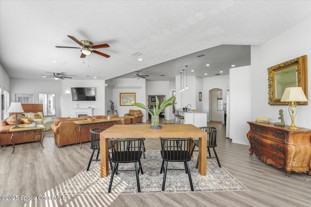 dining room with ceiling fan, light hardwood / wood-style floors, and a textured ceiling