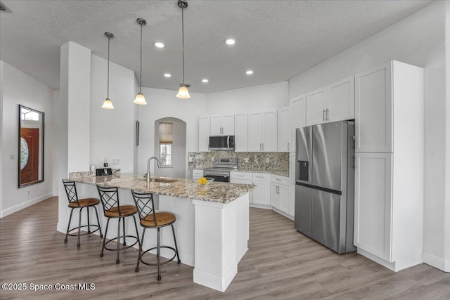 kitchen featuring sink, white cabinetry, light stone counters, kitchen peninsula, and stainless steel appliances