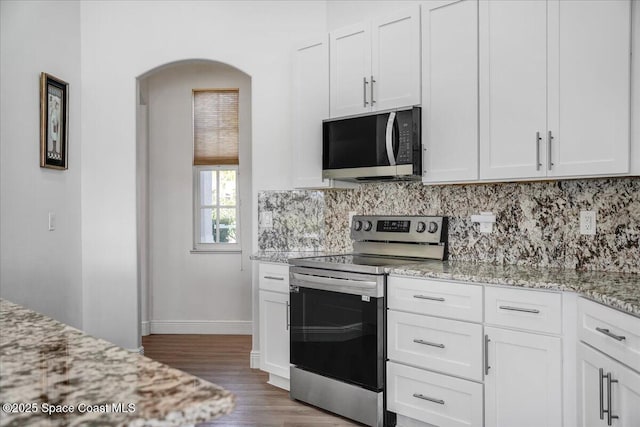 kitchen with dark wood-type flooring, tasteful backsplash, light stone countertops, white cabinets, and stainless steel electric range oven