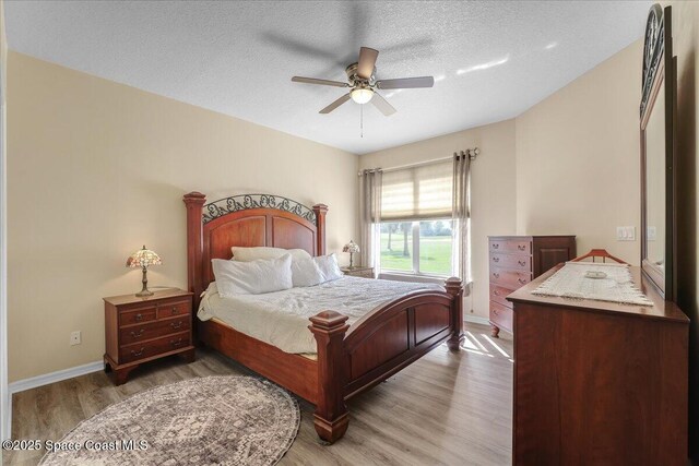 bedroom featuring ceiling fan, hardwood / wood-style floors, and a textured ceiling