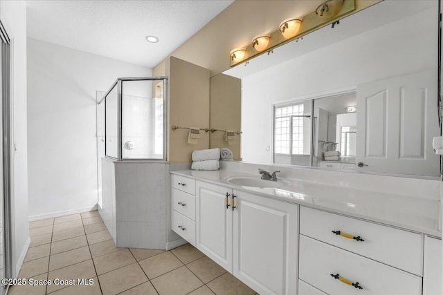 bathroom with a shower with door, vanity, tile patterned floors, and a textured ceiling