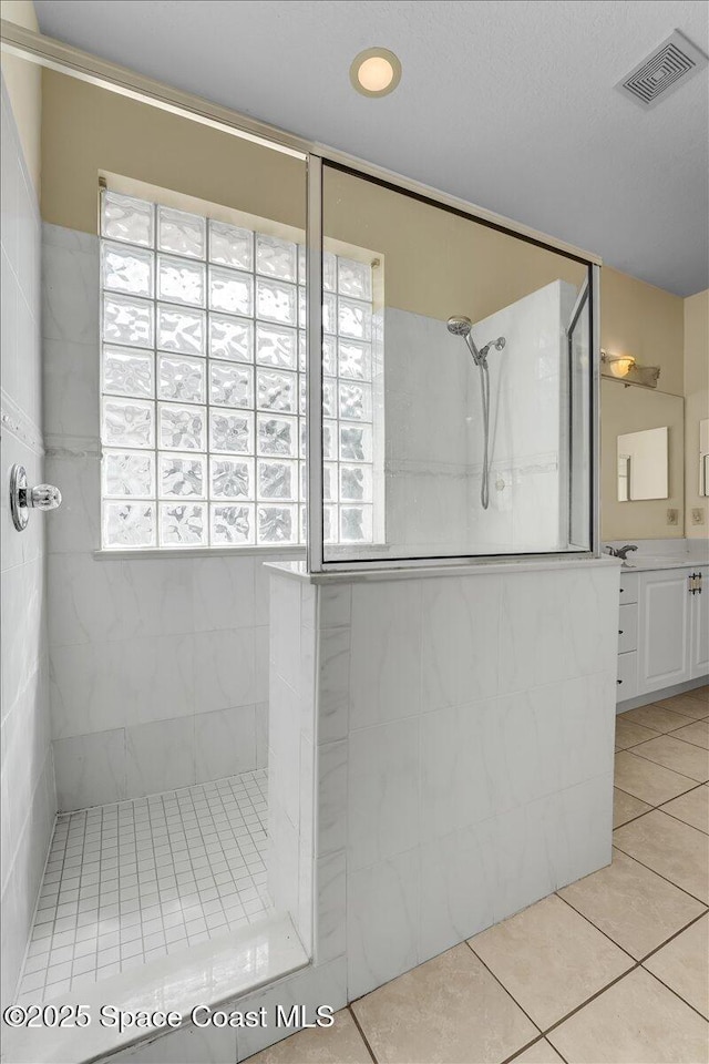 bathroom with tile patterned floors, vanity, and a tile shower