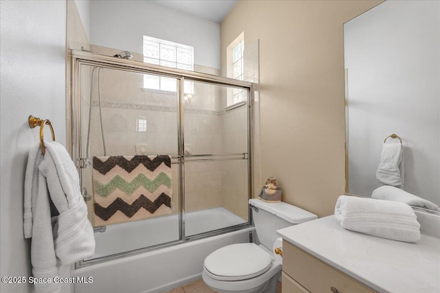 full bathroom featuring vanity, shower / bath combination with glass door, and toilet