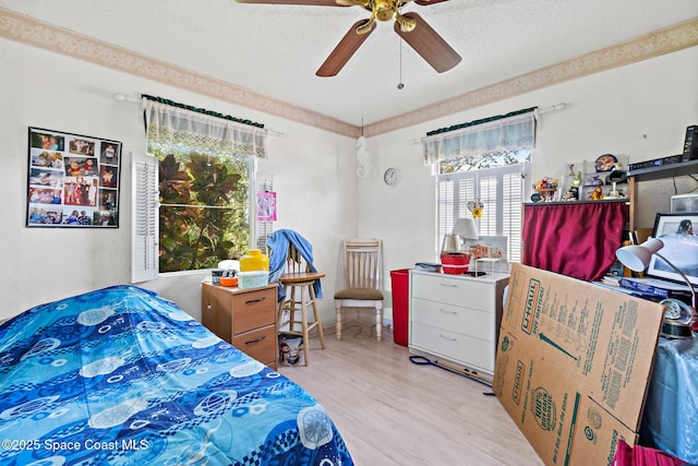 bedroom featuring ceiling fan, wood finished floors, and a textured ceiling