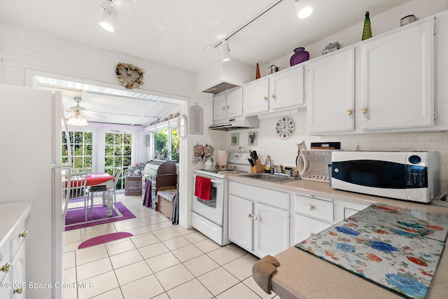 kitchen with under cabinet range hood, white cabinetry, white appliances, light countertops, and light tile patterned floors