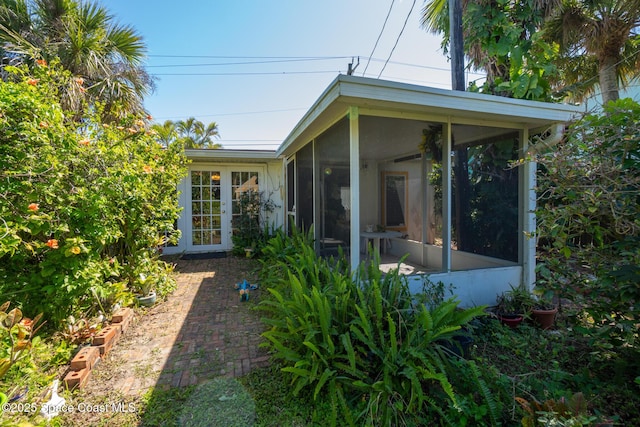 rear view of house featuring stucco siding and a sunroom