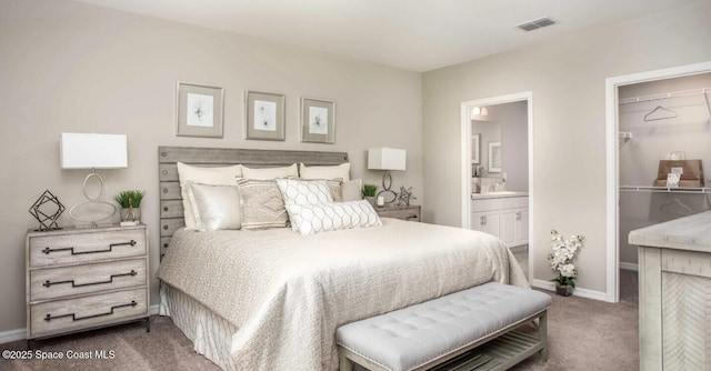 bedroom with connected bathroom, sink, dark colored carpet, a walk in closet, and a closet