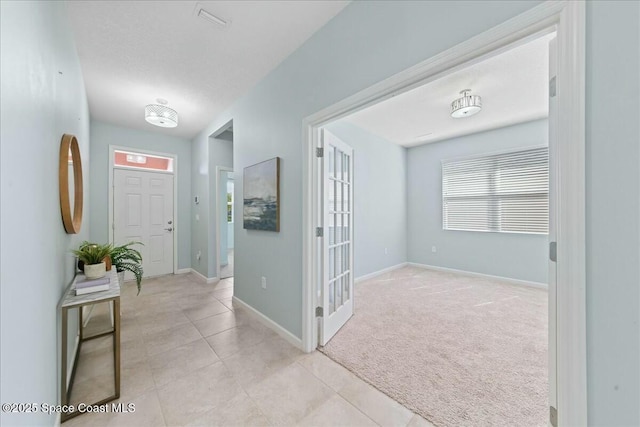 corridor featuring light carpet, light tile patterned floors, and baseboards