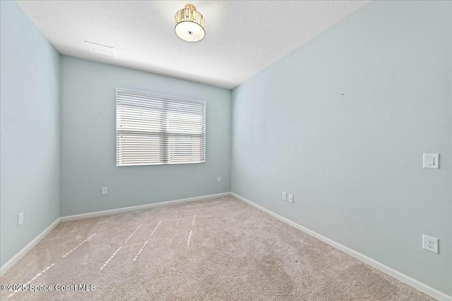 carpeted spare room with visible vents, baseboards, and a textured ceiling