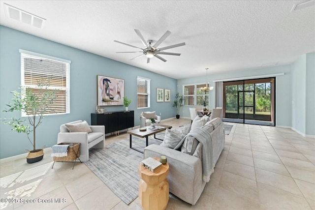 living area with visible vents, a textured ceiling, light tile patterned floors, and ceiling fan with notable chandelier