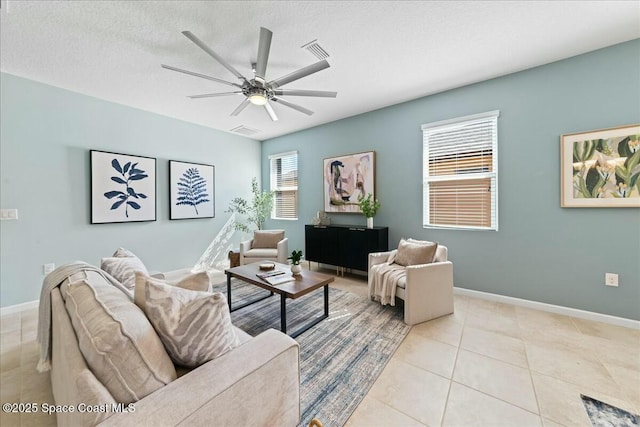 living room with baseboards, light tile patterned floors, a textured ceiling, a ceiling fan, and visible vents