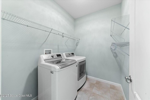 washroom featuring baseboards, washing machine and dryer, and laundry area