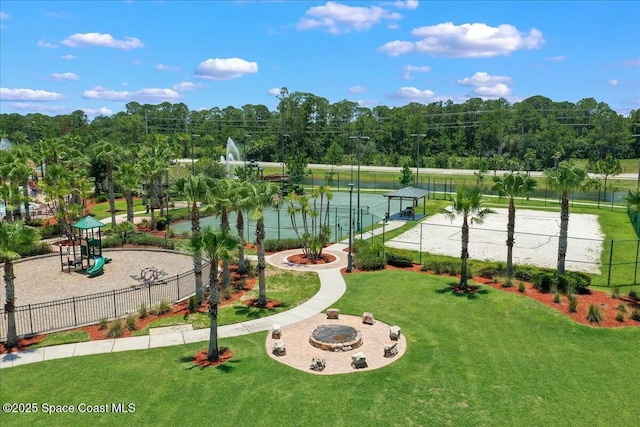 view of home's community featuring a fire pit, playground community, fence, and a lawn