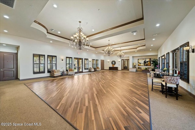 interior space featuring visible vents, a raised ceiling, a chandelier, and wood finished floors