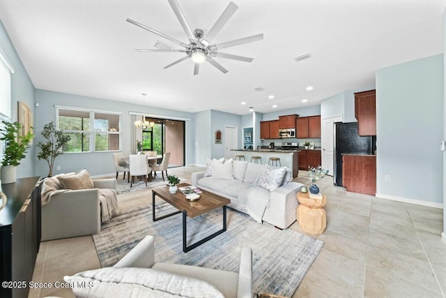 living room featuring ceiling fan with notable chandelier, visible vents, recessed lighting, light tile patterned flooring, and baseboards