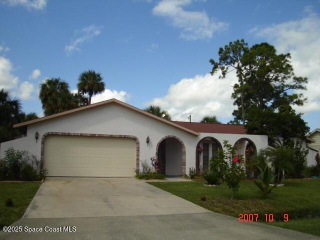 view of front of house featuring an attached garage, a front yard, concrete driveway, and stucco siding