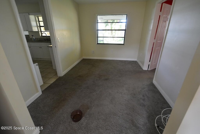 empty room featuring plenty of natural light, dark colored carpet, and a sink