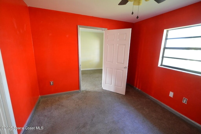 carpeted empty room featuring a ceiling fan and baseboards