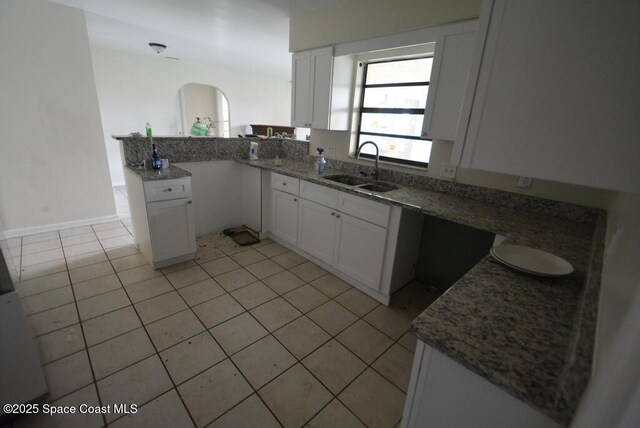 kitchen featuring white cabinetry, a sink, a peninsula, and light tile patterned floors