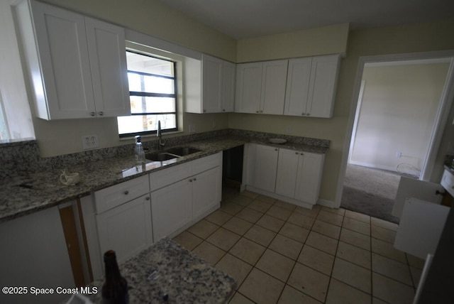 kitchen featuring light tile patterned floors, stone countertops, a sink, and white cabinetry