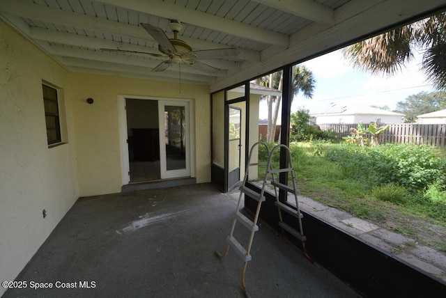 unfurnished sunroom featuring a ceiling fan and beam ceiling