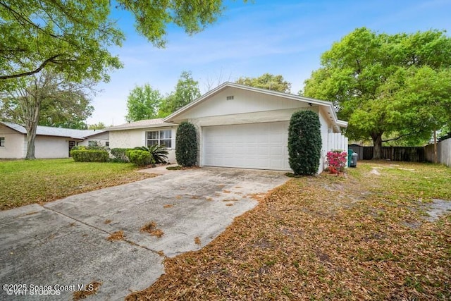 ranch-style house featuring a front lawn, an attached garage, fence, and driveway