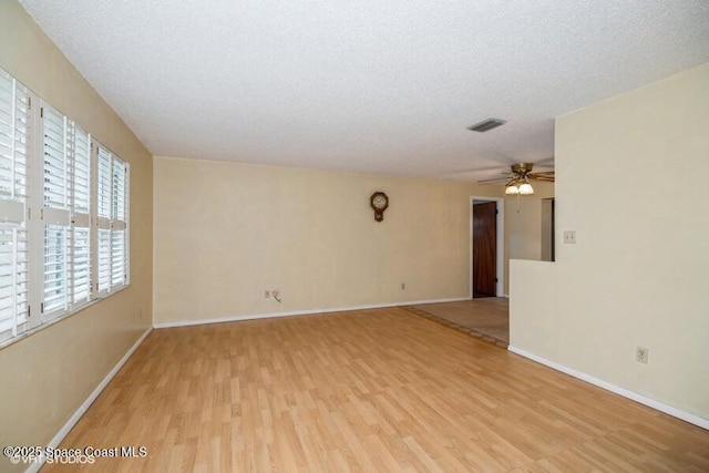 unfurnished room featuring ceiling fan, light wood-style floors, baseboards, and a textured ceiling