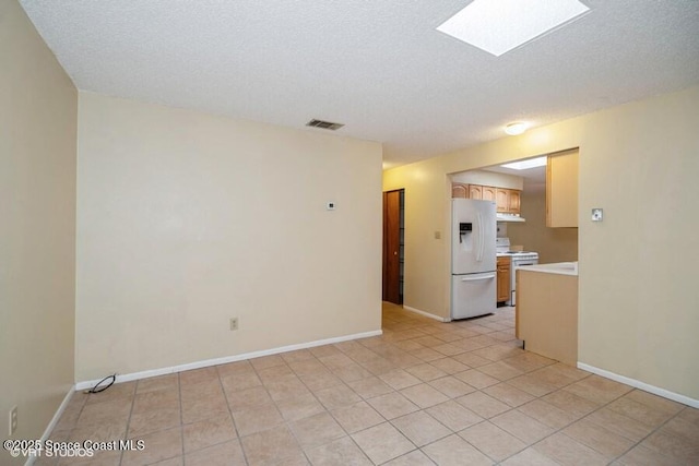 unfurnished room featuring visible vents, a textured ceiling, a skylight, and baseboards