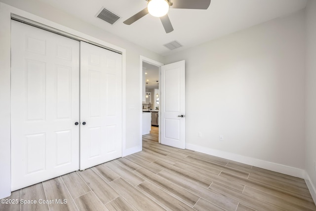 unfurnished bedroom with ceiling fan and a closet