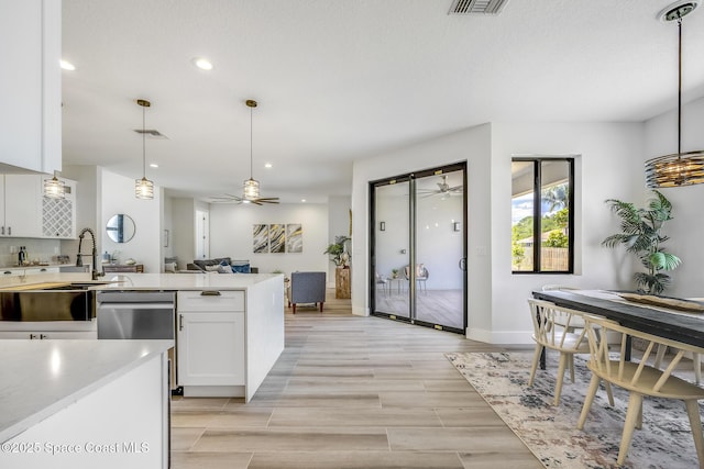 kitchen featuring white cabinetry, decorative backsplash, hanging light fixtures, stainless steel dishwasher, and ceiling fan