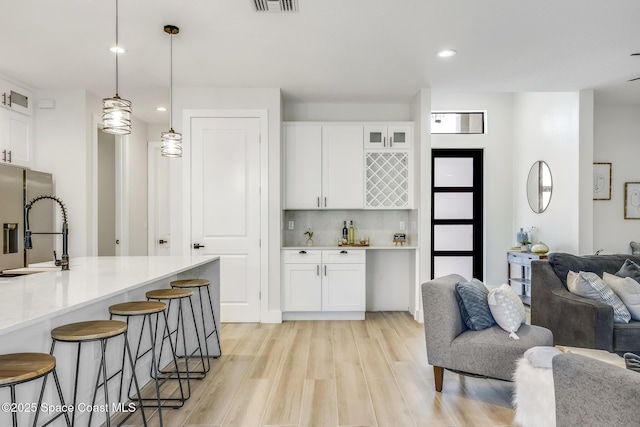 kitchen featuring white cabinetry, sink, a kitchen bar, and decorative light fixtures