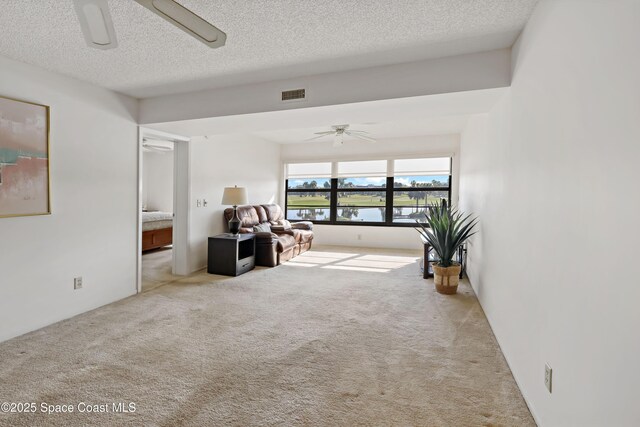 11 Plantation Dr Unit 201, Vero Beach, FL 32966 - living room featuring light colored carpet, a textured ceiling, and ceiling fan