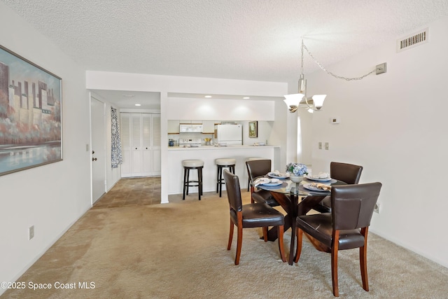 11 Plantation Dr Unit 201, Vero Beach, FL 32966 - dining room featuring light carpet, a textured ceiling, and a chandelier