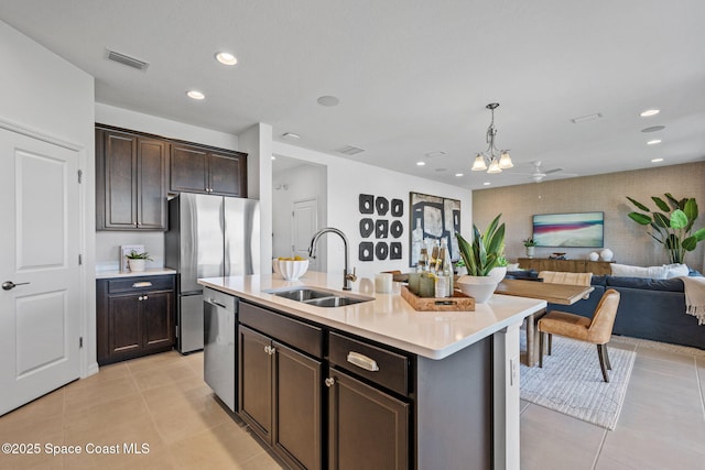 2496 Kamin Dr S, Melbourne, FL 32940 - kitchen featuring sink, a kitchen island with sink, dark brown cabinets, stainless steel appliances, and decorative light fixtures