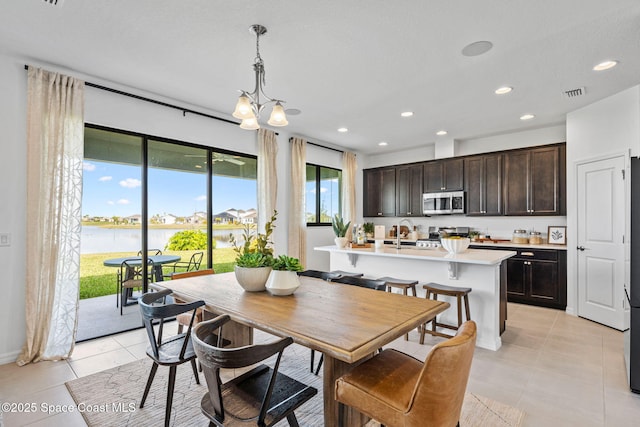 2496 Kamin Dr S, Melbourne, FL 32940 - dining area featuring sink, light tile patterned flooring, a chandelier, and a water view