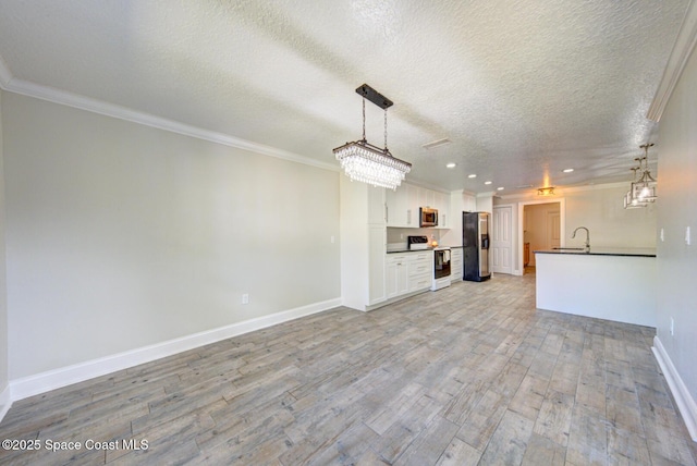 kitchen with appliances with stainless steel finishes, sink, pendant lighting, and white cabinets