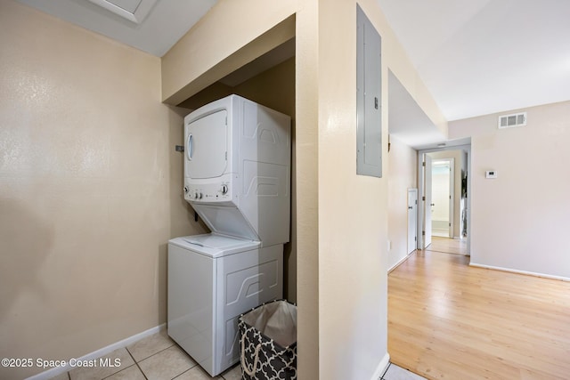 washroom with stacked washing maching and dryer, electric panel, and light hardwood / wood-style floors