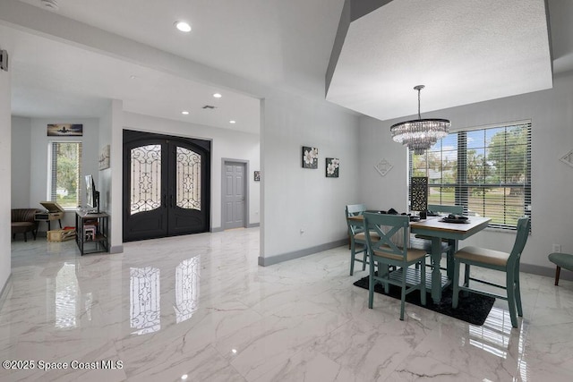 foyer entrance featuring an inviting chandelier and french doors