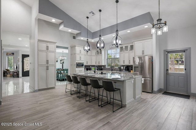 kitchen featuring hanging light fixtures, a spacious island, light stone countertops, appliances with stainless steel finishes, and white cabinets